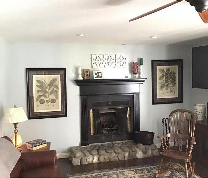 living room with white walls, fire place with mantle pictures on walls