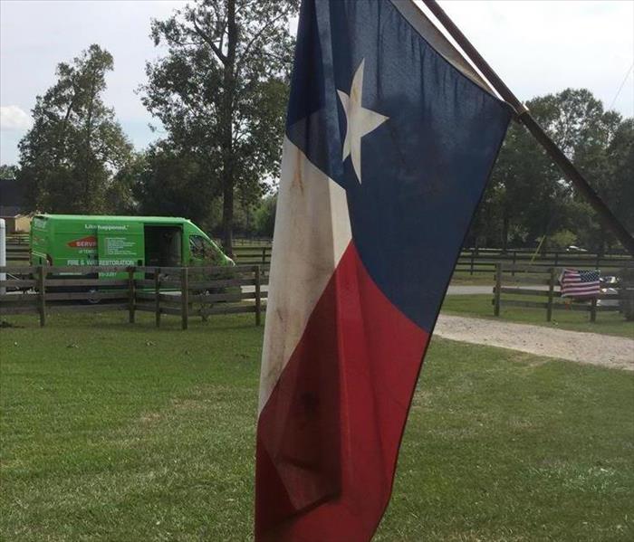 texas red, blue white flag hanging in yard with SERVPRO van in background 