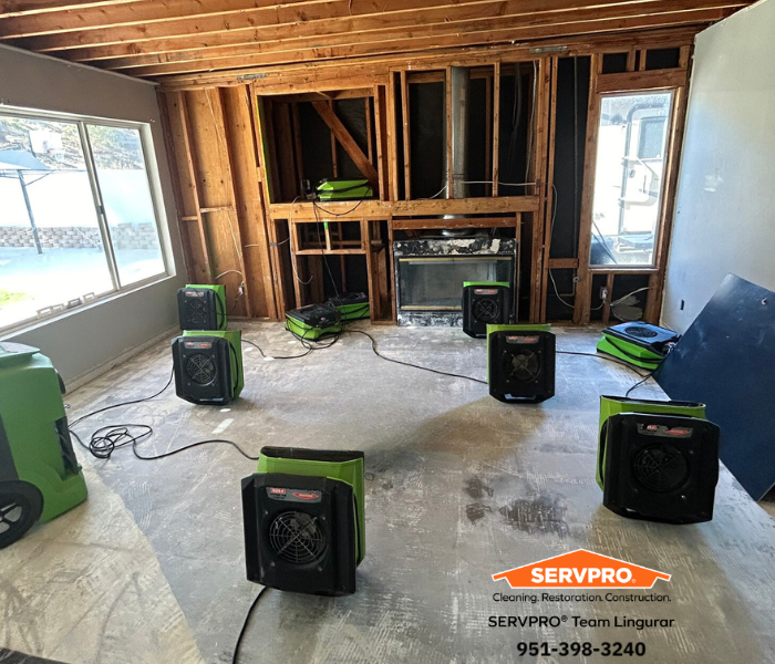 Living room full of air movers and dehumidify drying flooring and celling 