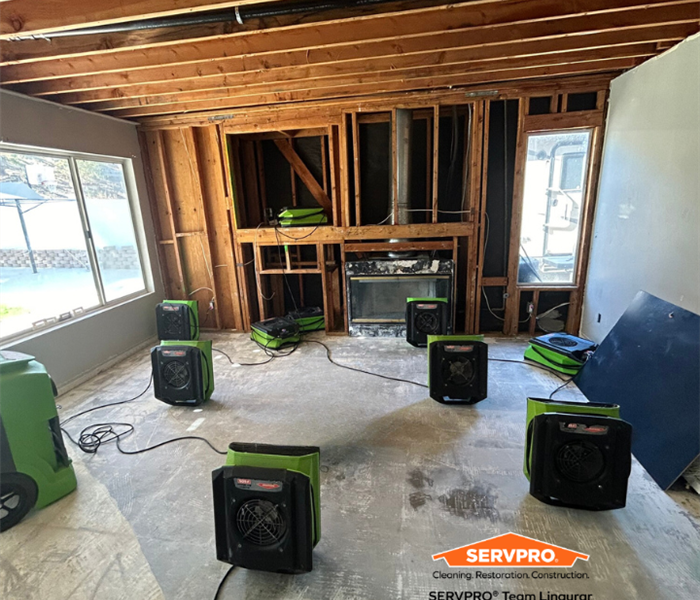 Living room full of air movers and dehumidify drying flooring and celling 