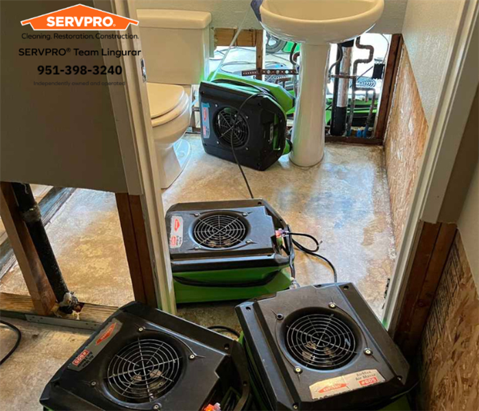 A bathroom with mitigation process of drying floors and walls with air movers. 